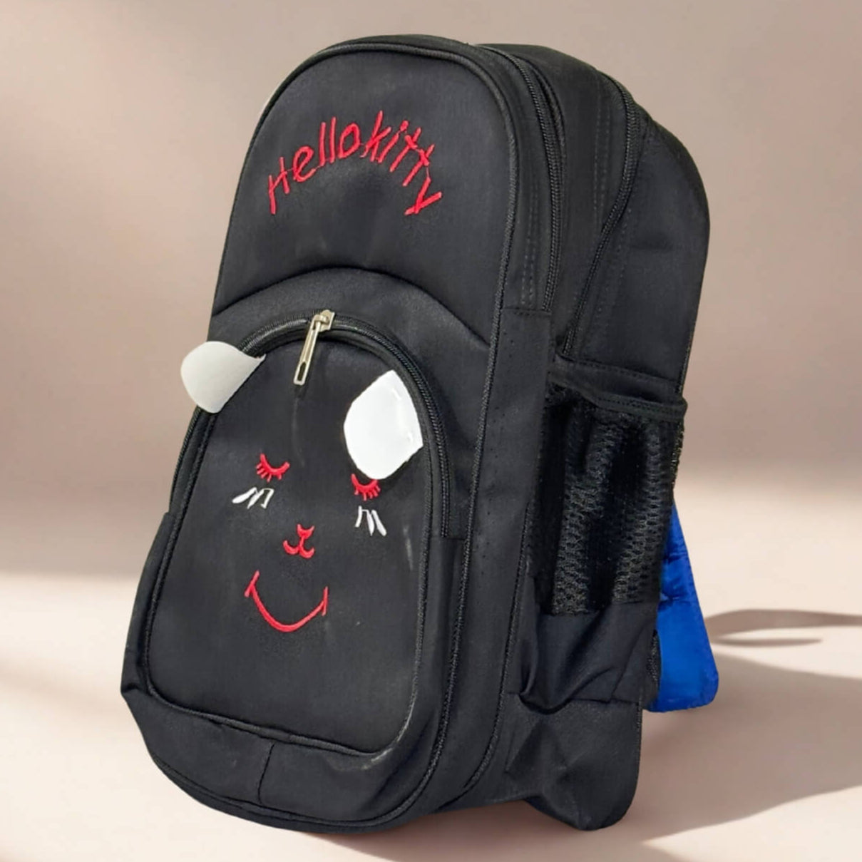 Black backpack with a cartoon face design and 'Hello Kitty' text on a beige background